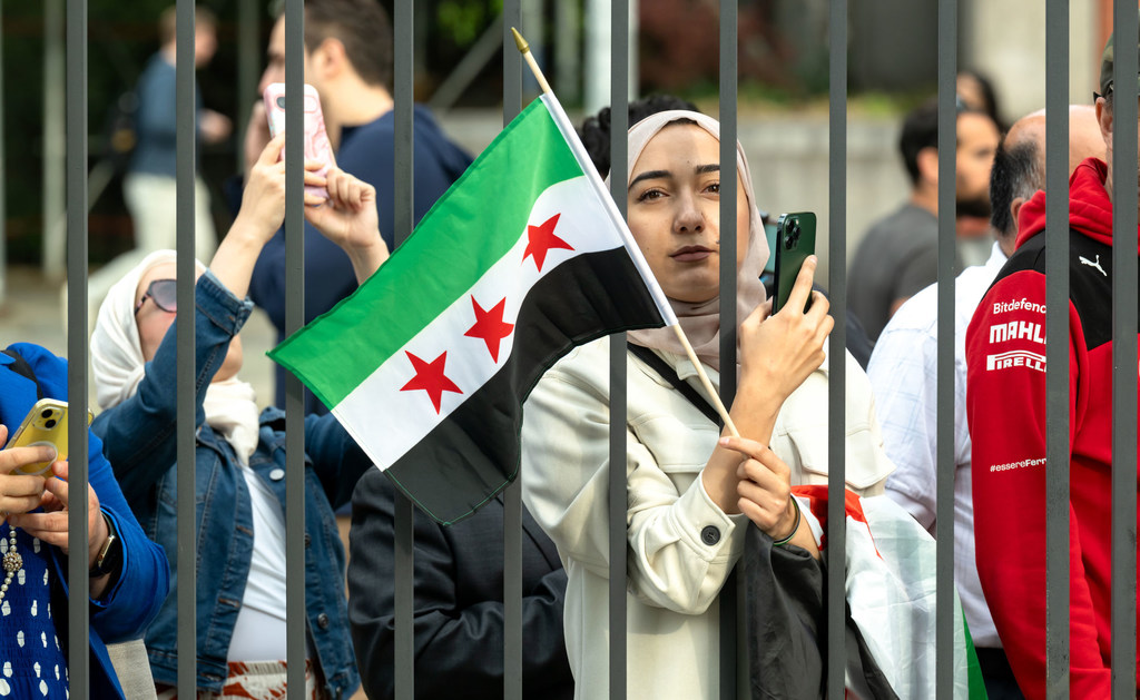 شابة سورية تحمل العلم السوري الجديد خارج مقر الأمم المتحدة في نيويورك.